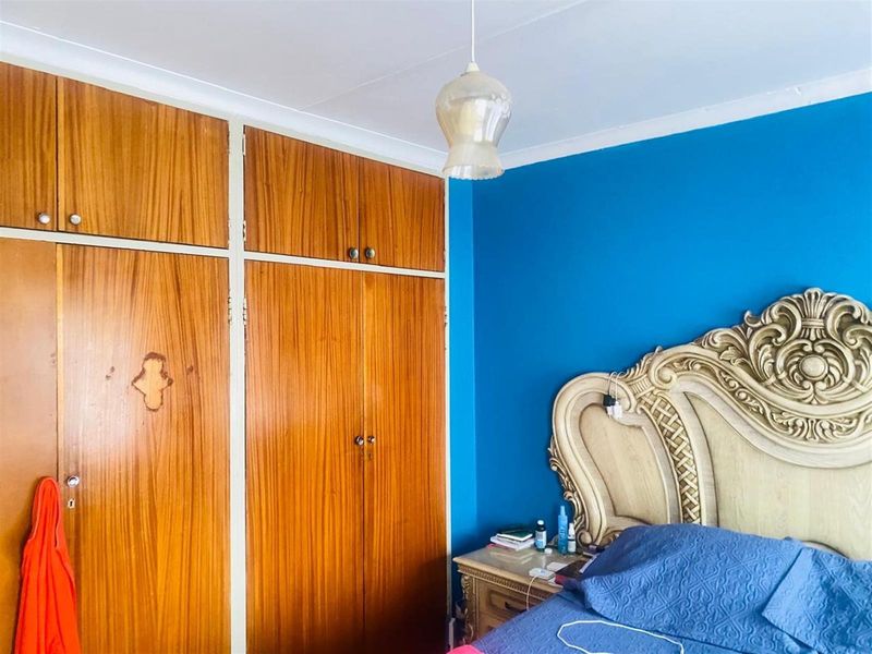 A bedroom featuring built-in wooden cupboards with overhead storage and vibrant blue wall paint.