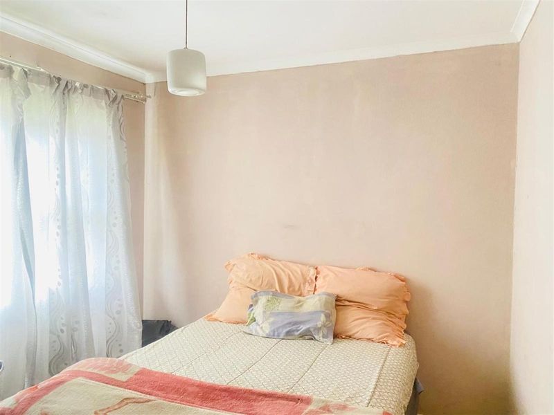 A simple bedroom featuring neutral wall finishes, a pendant light fixture, and coving detail.
