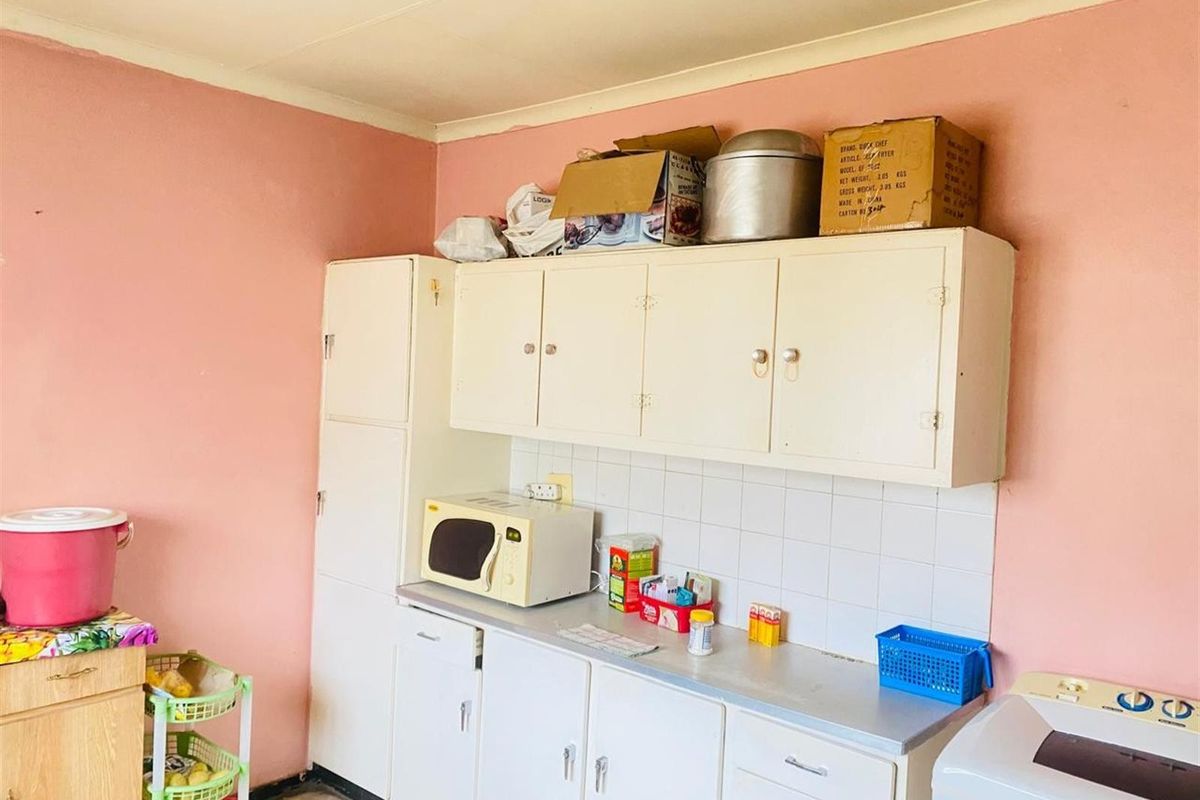 A dated kitchen area featuring built-in cabinetry, a tiled backsplash, and laminate countertops, offering potential for modernization and renovation.