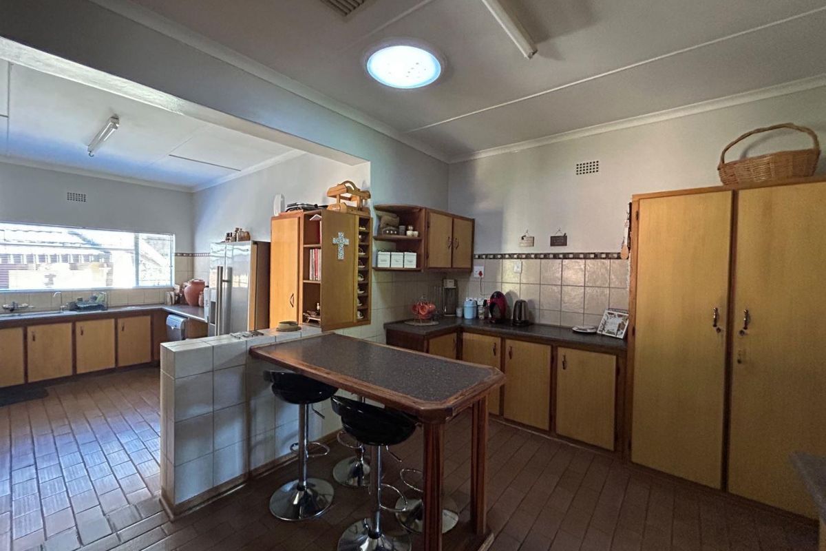 A spacious kitchen featuring wooden cabinetry, a tiled breakfast bar, and ample counter space, offering a functional layout with potential for modern updates.