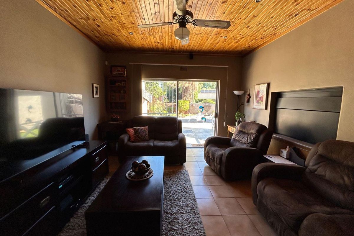 A comfortable living room featuring a distinctive wood-paneled ceiling, ceiling fan, and sliding glass doors that open to the outdoor patio area.