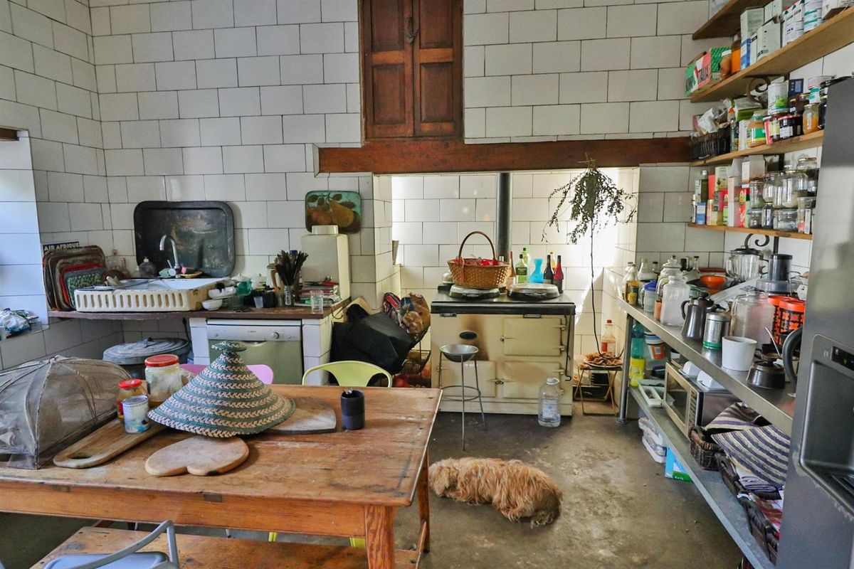 A rustic, functional kitchen featuring a vintage-style range cooker, tiled walls, and open shelving, offering a characterful space with significant potential for renovation.