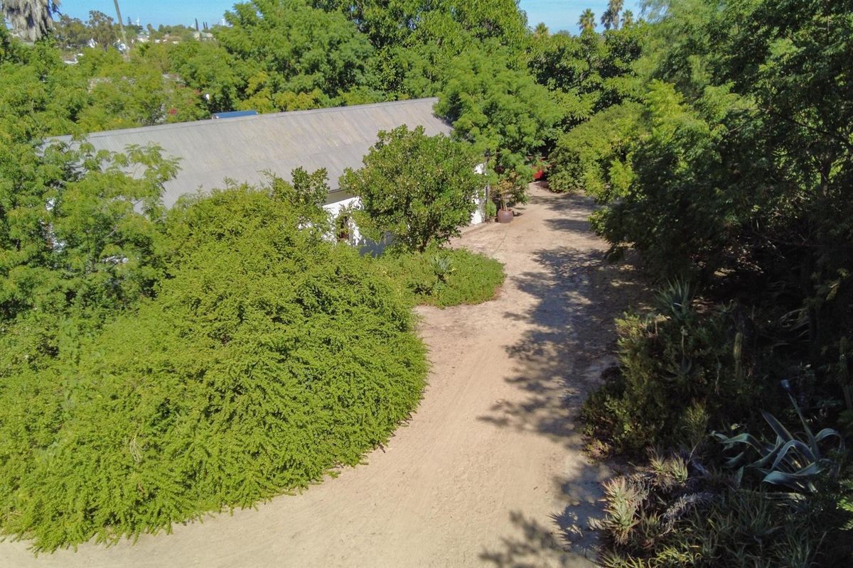 An aerial view of the property showing a large garden area with mature trees and a gravel driveway leading to the house.