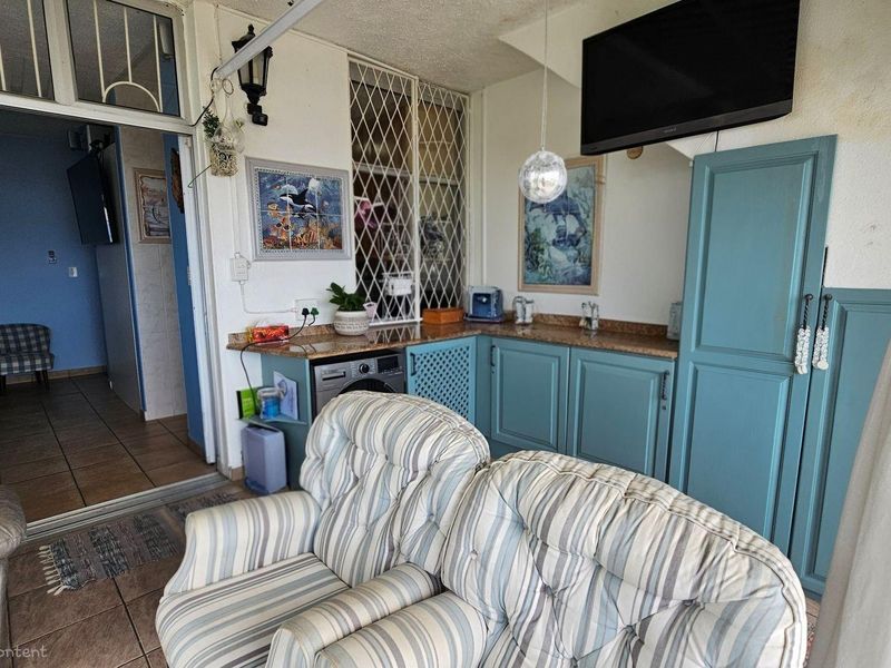A covered patio area featuring built-in blue cabinetry, a granite countertop, and integrated laundry plumbing, providing a functional transition space.