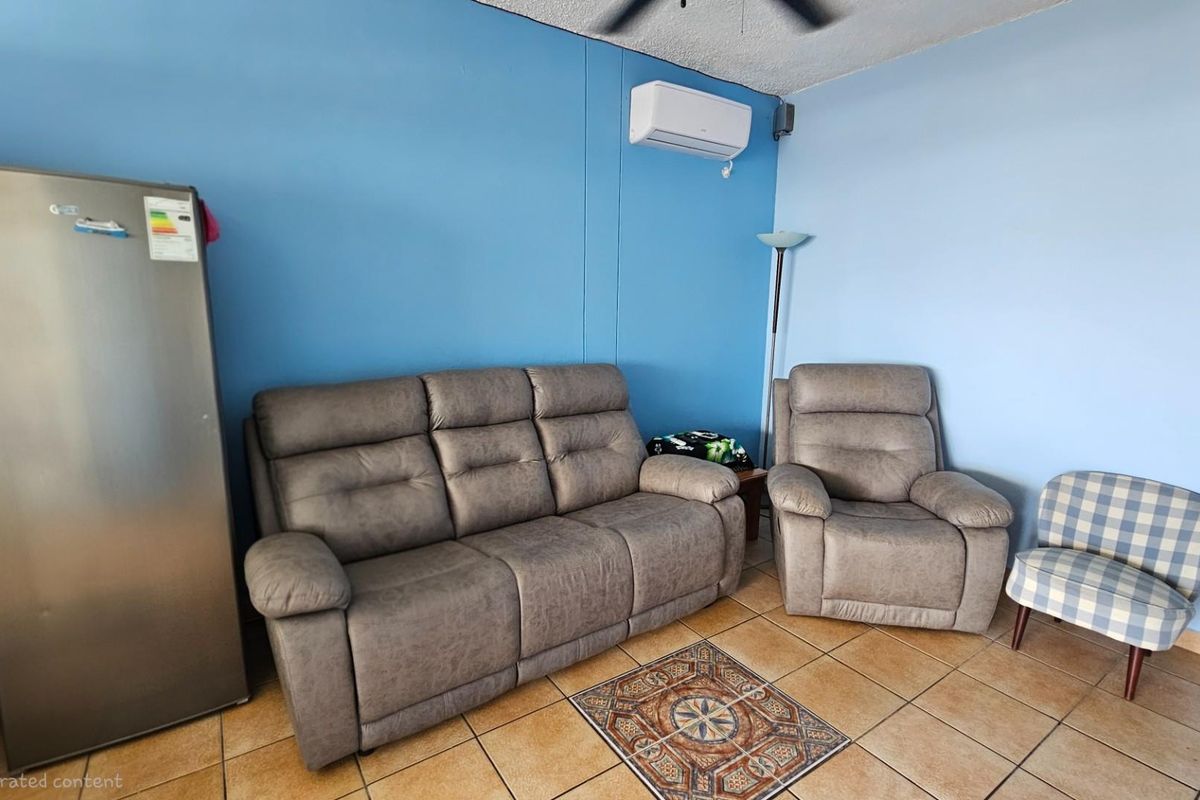 A living area featuring tiled flooring, a wall-mounted air conditioning unit, and blue painted walls.