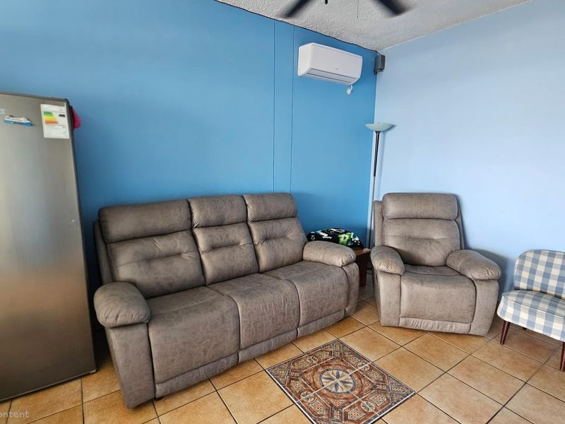 A living area featuring tiled flooring, a wall-mounted air conditioning unit, and blue painted walls.
