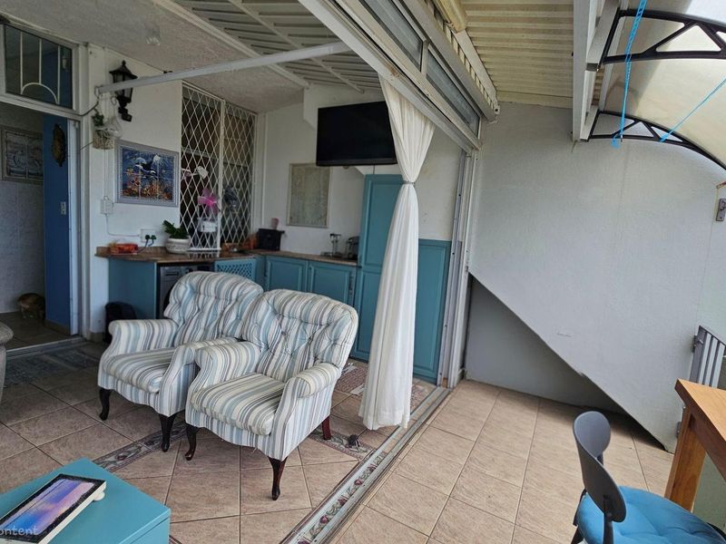 Covered patio area featuring tiled flooring, built-in cabinetry, and sliding door access to the interior living space.
