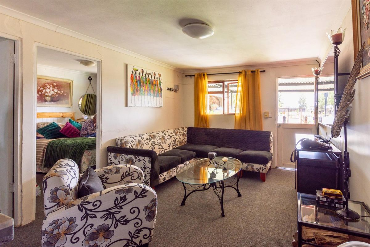 A cozy living room featuring carpeted flooring, a ceiling-mounted light fixture, and direct access to an exterior entrance.