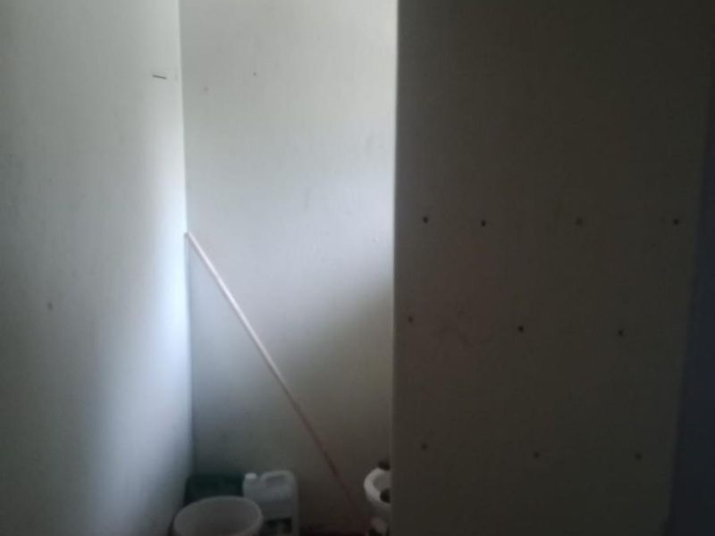 A small, unfinished bathroom space featuring a toilet and exposed wall paneling, requiring renovation to complete the installation and improve the overall finish.