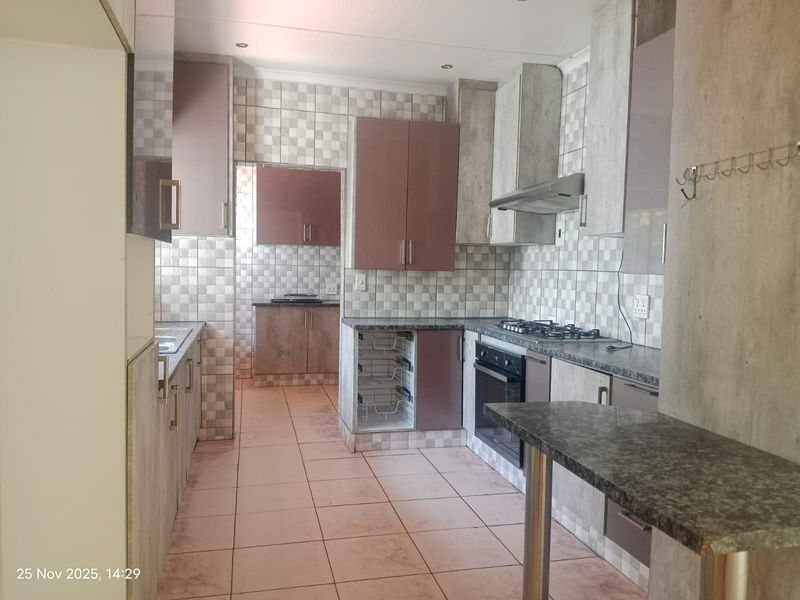 A functional kitchen featuring built-in cabinetry, gas hob, oven, extractor fan, and granite countertops with a breakfast bar area.