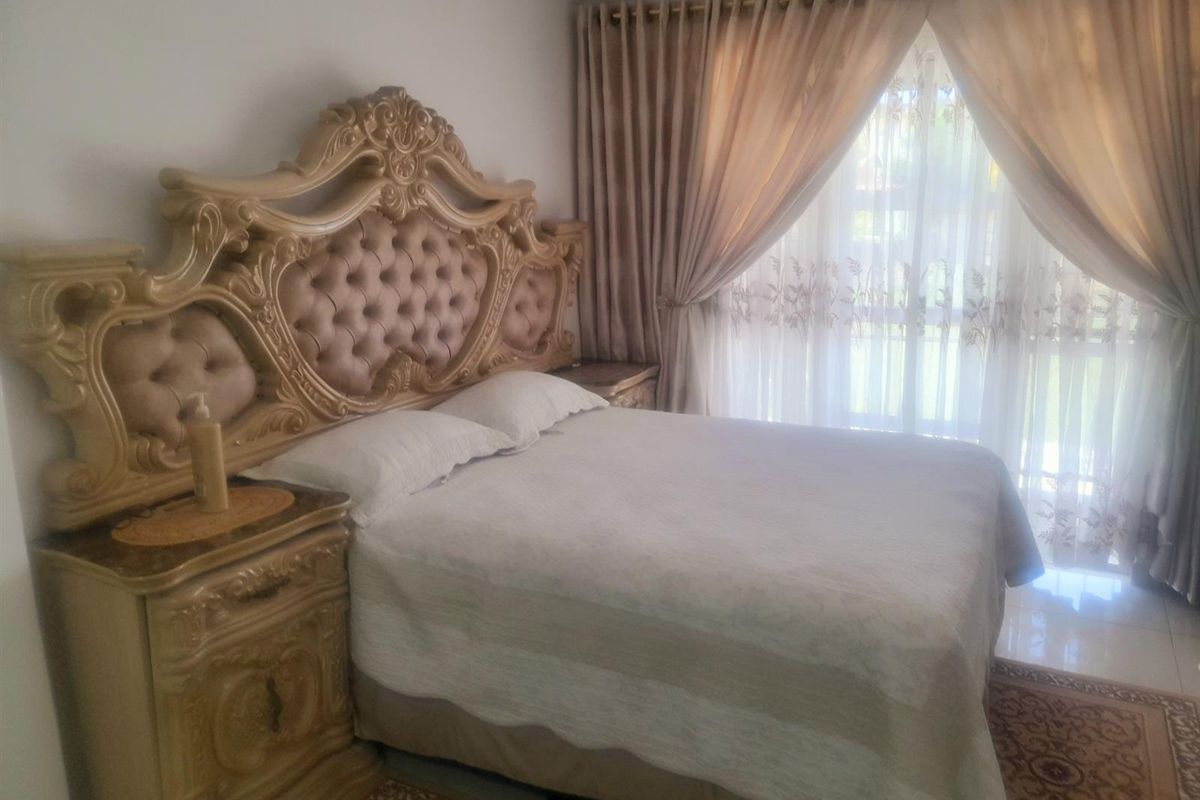 A bedroom featuring tiled flooring and large window with curtain tracks, offering a neutral base for potential interior updates.