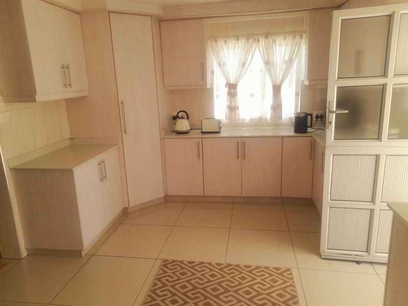 A functional kitchen featuring light-toned built-in cabinetry, laminate countertops, and tiled flooring, providing a clean and practical workspace.