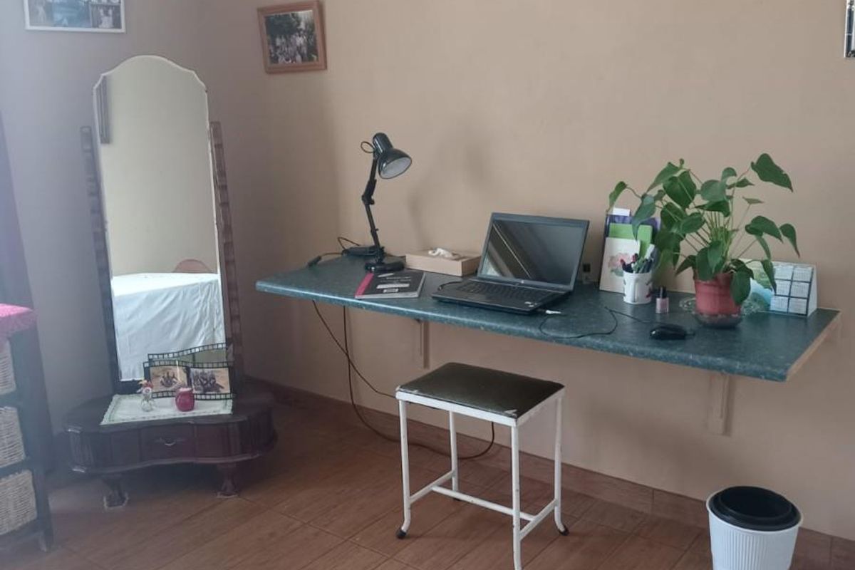 A functional bedroom space featuring wood-look tiled flooring and a wall-mounted desk surface.