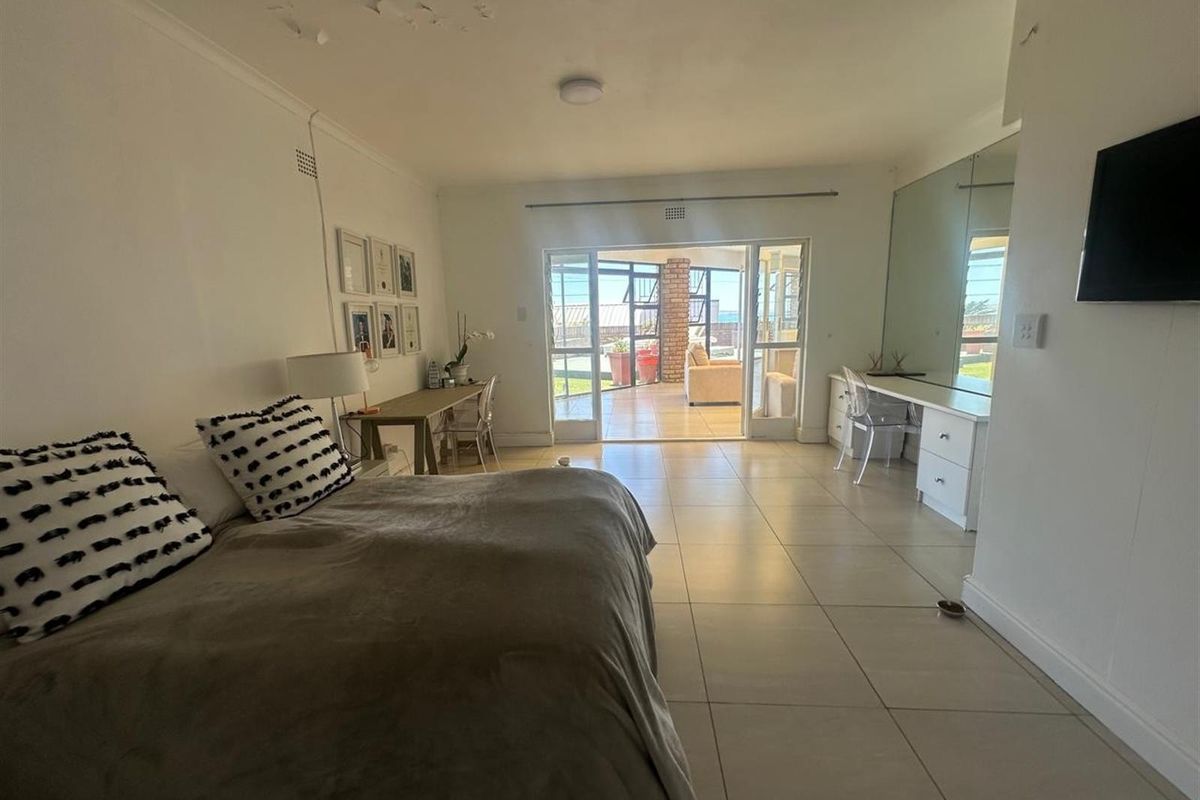 Spacious bedroom featuring tiled flooring, built-in vanity with mirror, and direct access to an outdoor patio area.