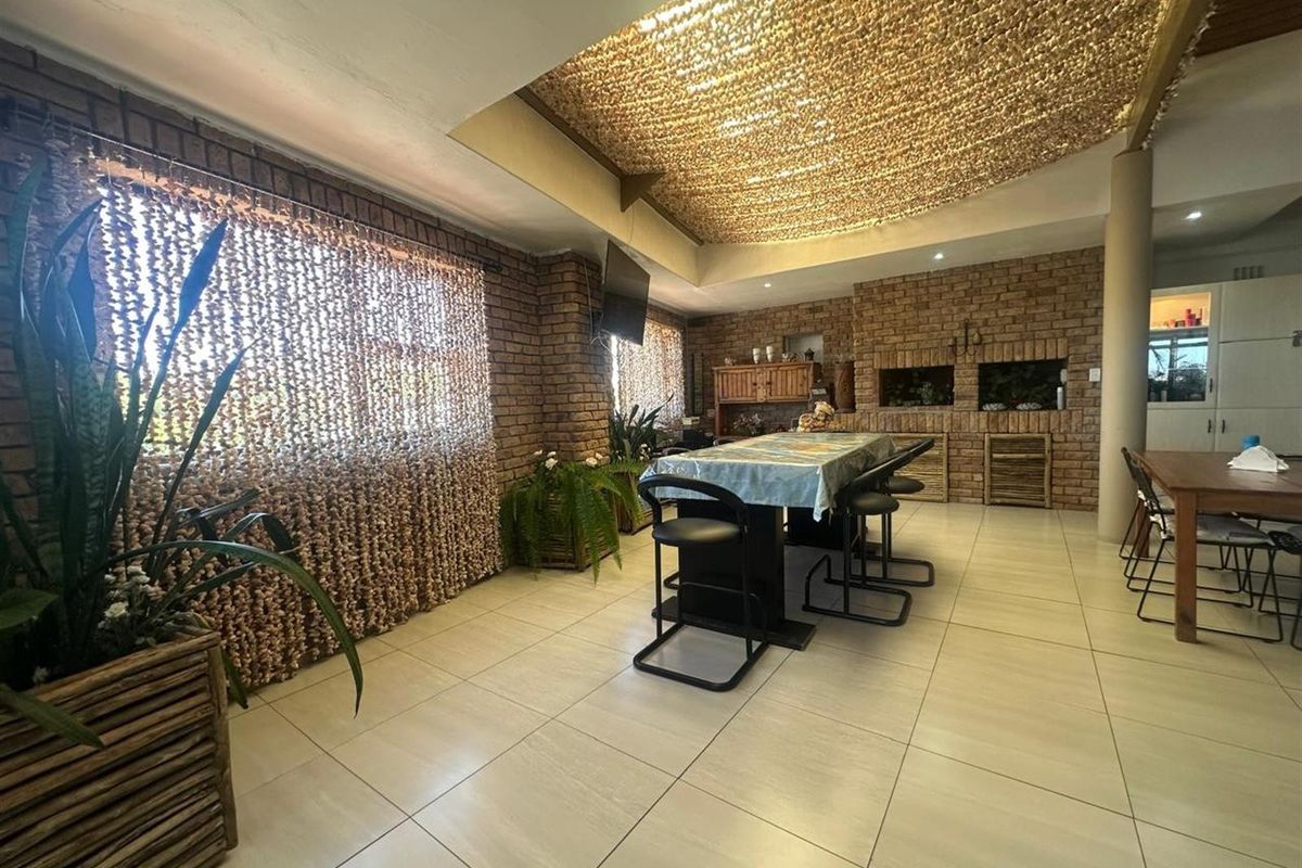 Spacious indoor entertainment area featuring exposed brick walls, tiled flooring, and a built-in braai, creating a rustic and functional space for gatherings.