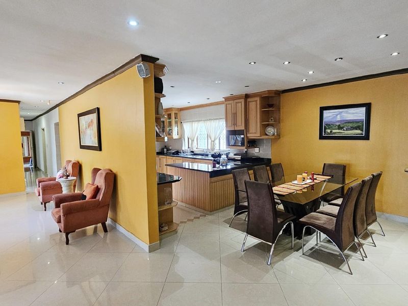 Spacious open-plan living and dining area featuring tiled floors, recessed lighting, and a functional kitchen with granite countertops and built-in cabinetry.