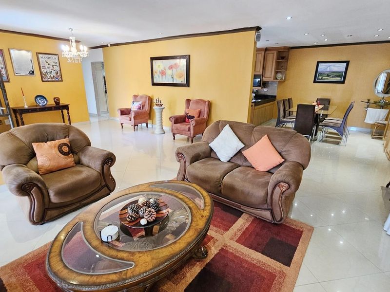 Spacious open-plan living and dining area featuring tiled floors, recessed lighting, and an integrated kitchen space with wooden cabinetry.