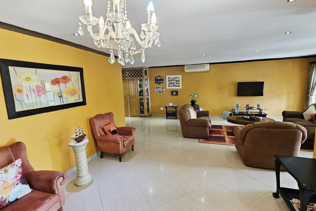 Spacious living area featuring polished tile flooring, recessed lighting, a decorative crystal chandelier, and integrated air conditioning, offering a comfortable and open layout.