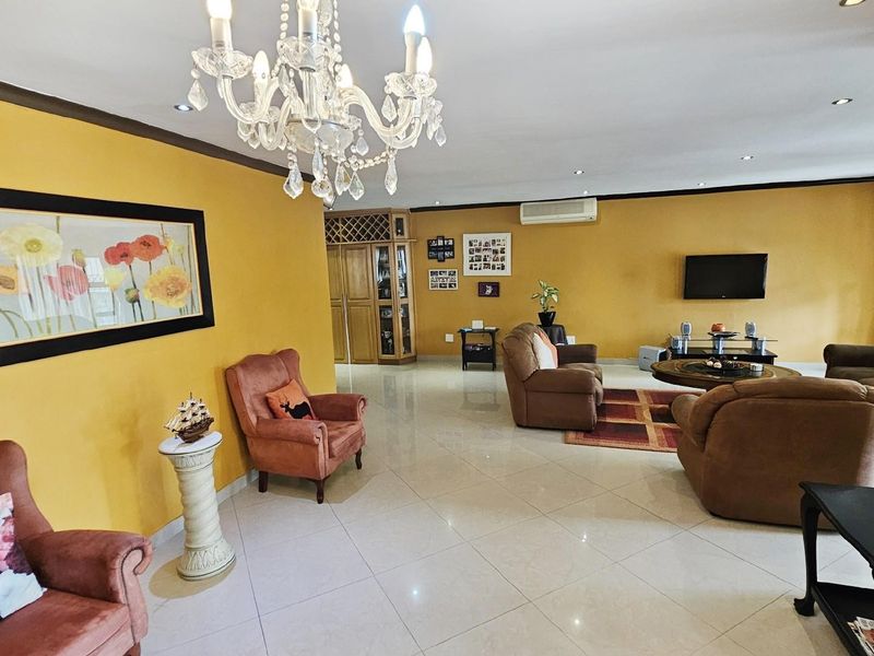 Spacious living area featuring polished tile flooring, recessed lighting, a decorative crystal chandelier, and integrated air conditioning, offering a comfortable and open layout.