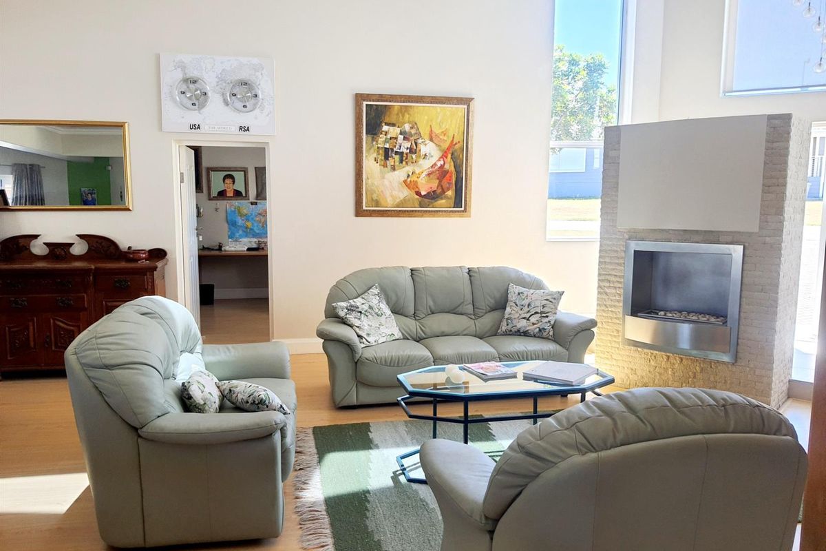 Spacious living room featuring high ceilings, large windows for natural light, and a modern built-in fireplace with stone cladding.