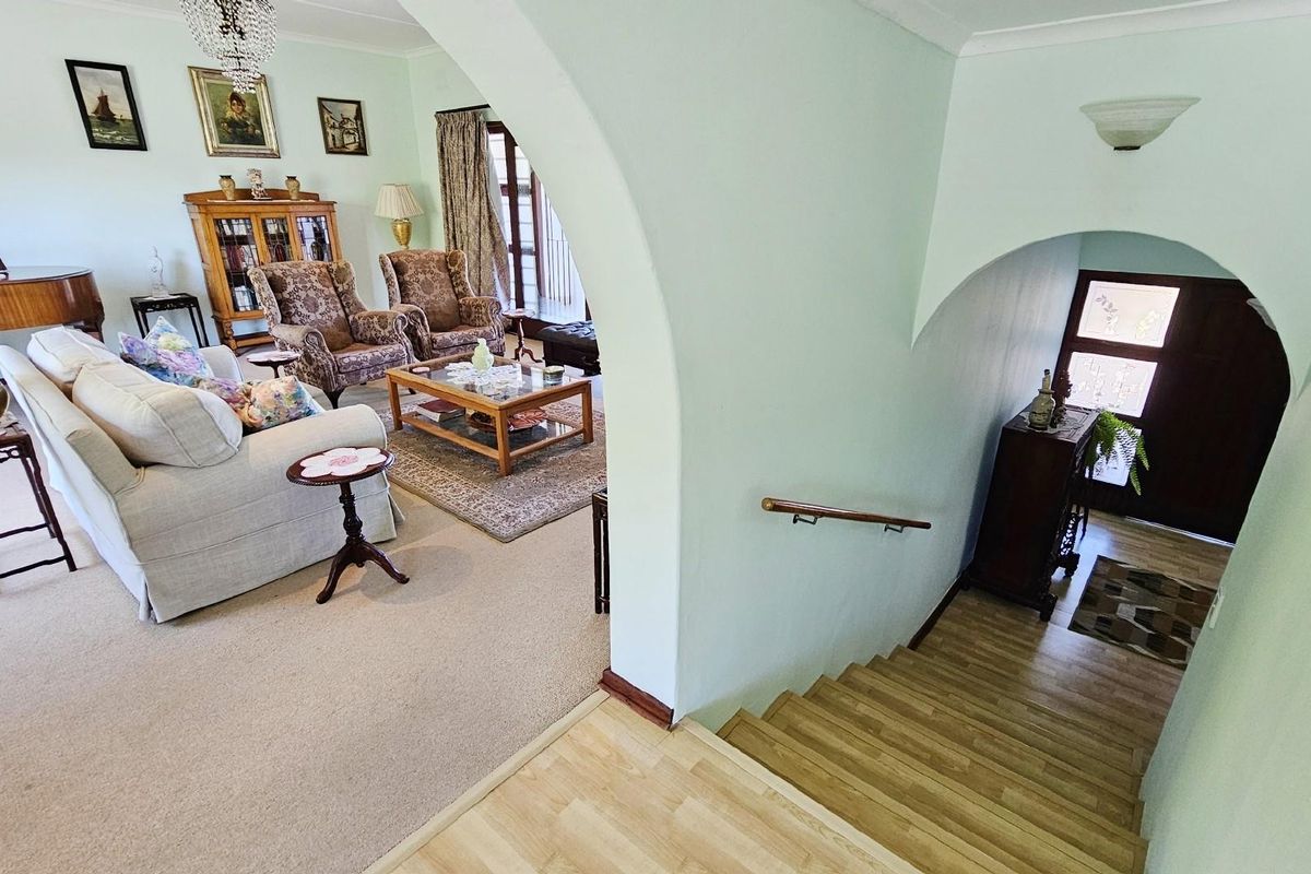 A view from the staircase looking into a spacious living area featuring arched architectural details and carpeted flooring.