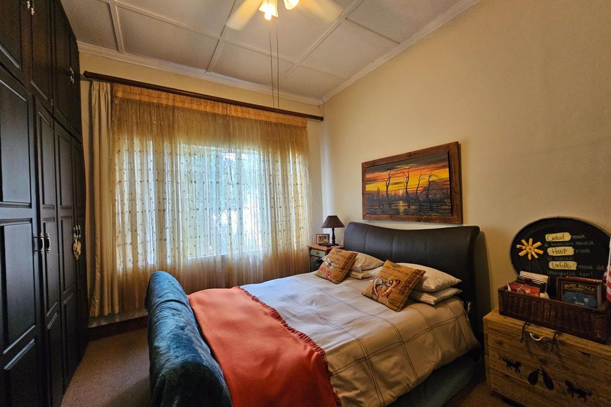 A cozy bedroom featuring built-in cupboards, a ceiling fan, and a tiled ceiling, providing a functional and comfortable living space.