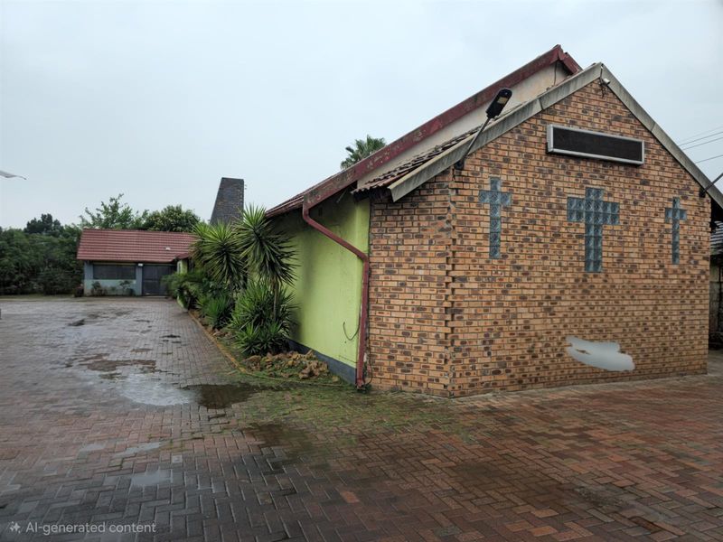 Exterior view of a brick building featuring glass block cross accents, a paved driveway, and a secondary structure in the background.