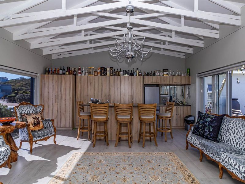 Spacious entertainment area featuring a built-in bar with cabinetry, vaulted exposed beam ceilings, and large sliding glass doors providing ample natural light.