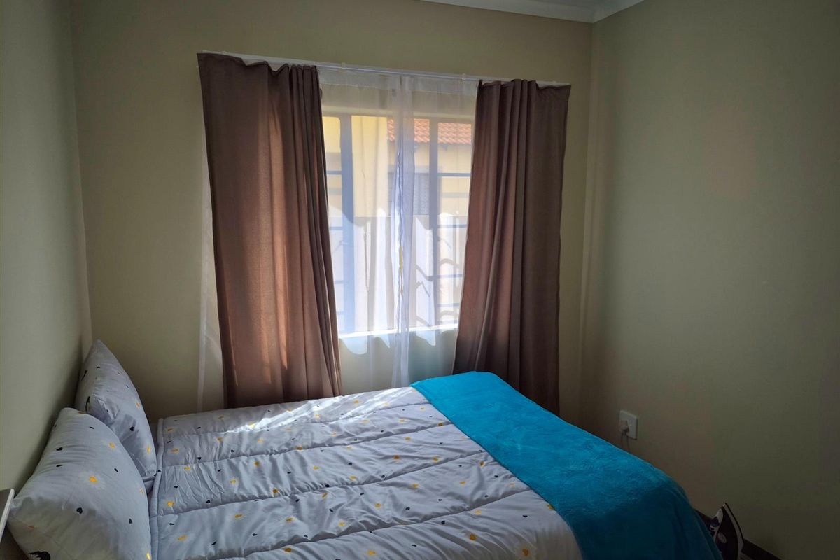 A standard bedroom featuring neutral wall tones and a window with curtain fixtures, providing a functional and comfortable living space.