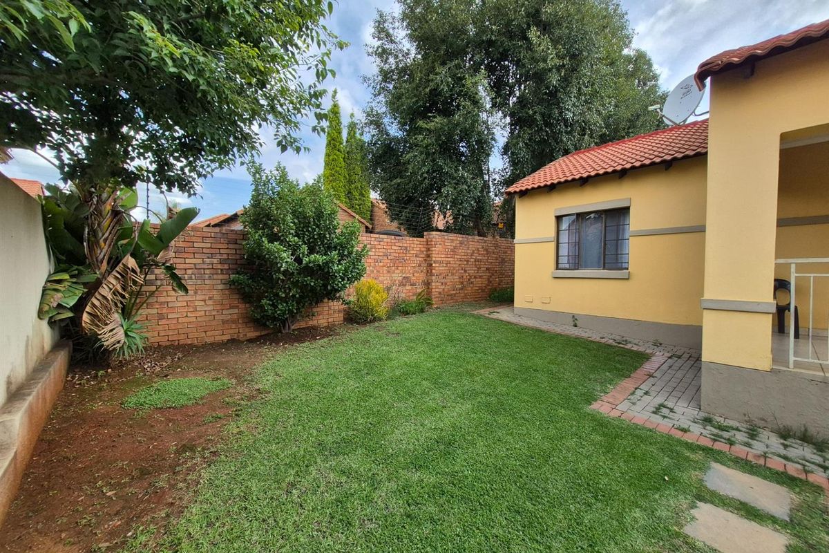 A private rear garden featuring a lawn area, brick boundary wall, and access to the townhouse patio.