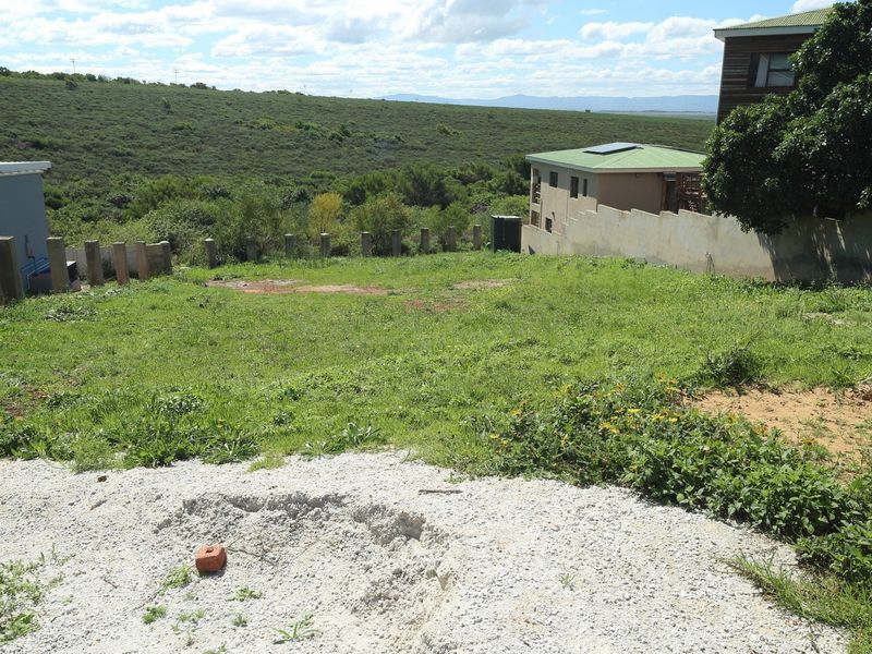 A vacant residential plot featuring a grassy landscape, boundary wall, and concrete pillars, offering an open space ready for development.