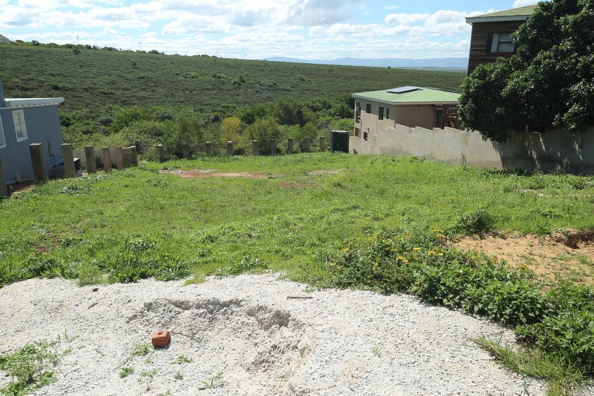 A vacant residential plot featuring a grassy landscape, boundary wall, and concrete pillars, offering an open space ready for development.