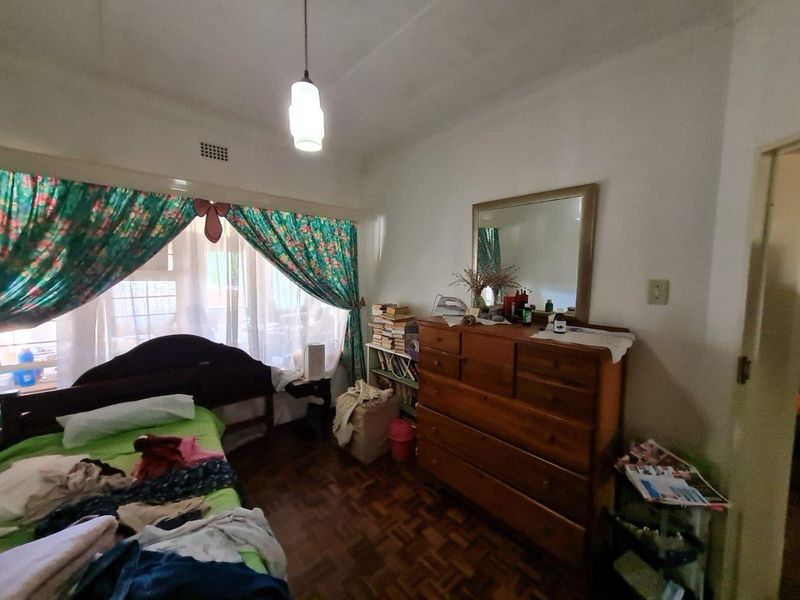 A bedroom featuring classic parquet flooring and a ceiling light fixture, offering a functional space with potential for modernization.