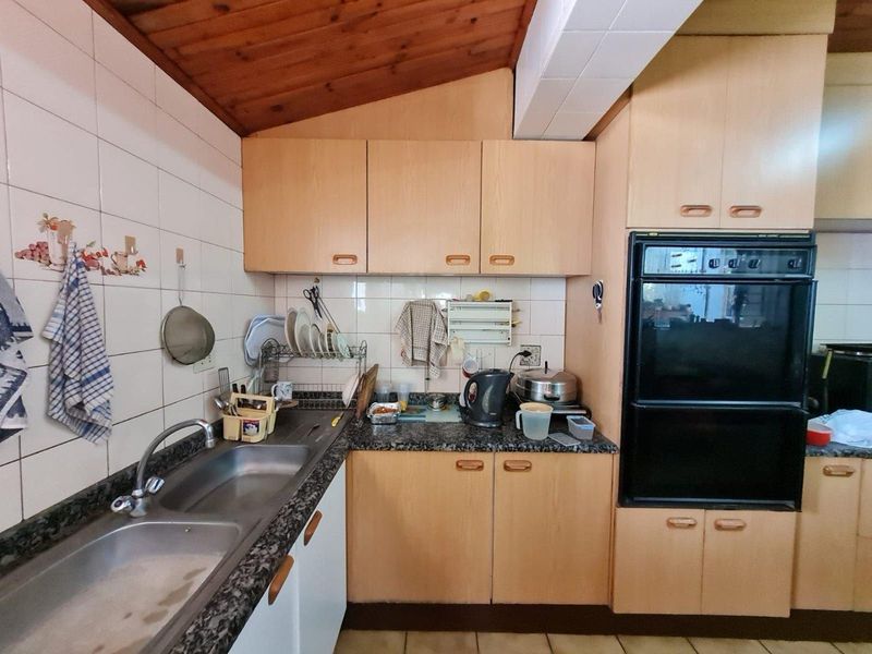 A functional kitchen featuring timber ceilings, laminate cabinetry, granite countertops, and a built-in oven, offering potential for a modern renovation.