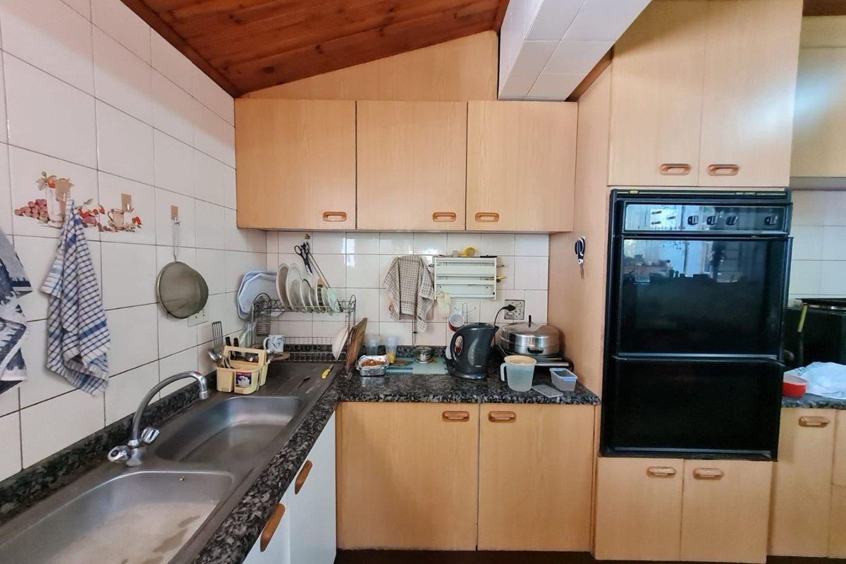 A functional kitchen featuring timber ceilings, laminate cabinetry, granite countertops, and a built-in oven, offering potential for a modern renovation.