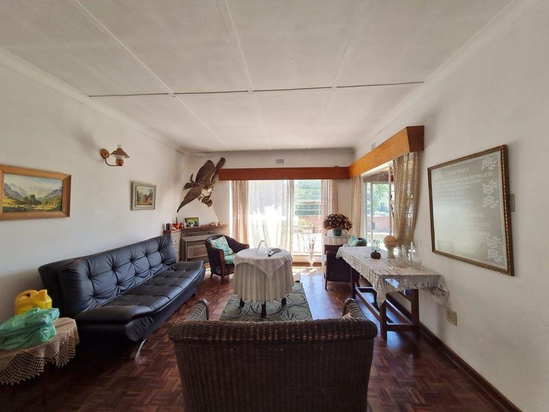 A spacious living room featuring classic parquet flooring and large sliding glass doors that provide ample natural light and access to the exterior.