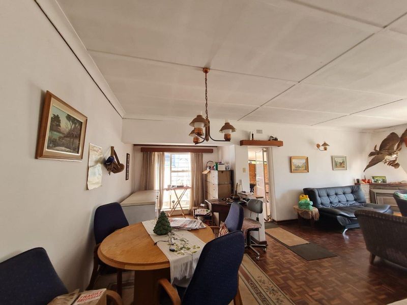 Open plan living and dining area featuring parquet flooring and traditional ceiling tiles, offering a versatile space for family living.