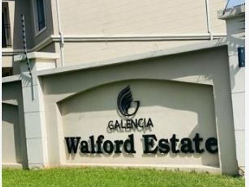 Front entrance view of Walford Estate featuring the complex signage, manicured lawn, and perimeter electric fencing.