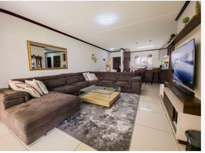 Spacious open-plan living area featuring tiled flooring, a modern kitchen with a breakfast bar, and integrated cabinetry, creating a seamless flow throughout the home.