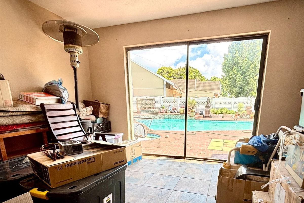 A living area featuring large sliding glass doors that provide direct access to an outdoor patio and swimming pool area.