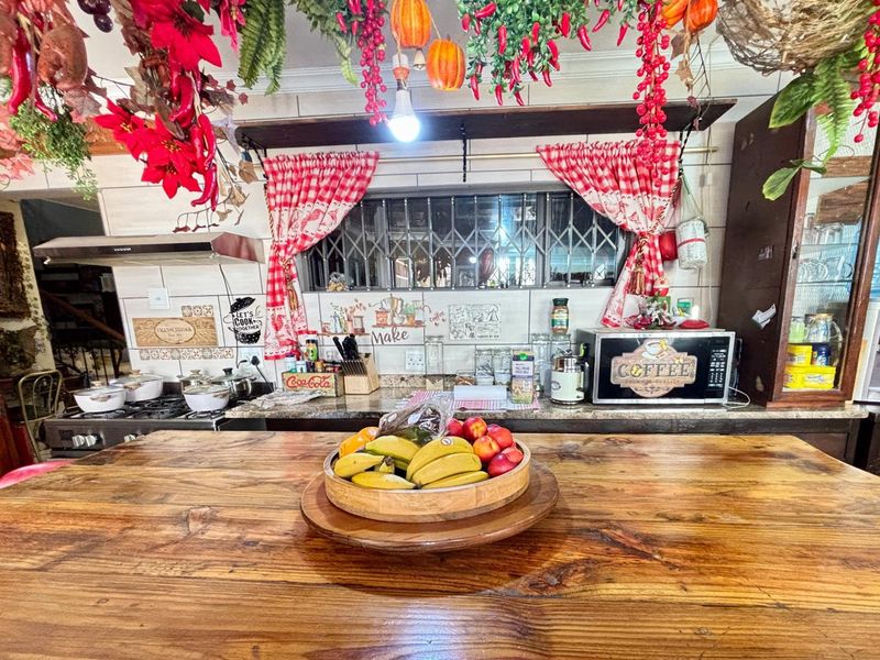 A rustic-style kitchen featuring a large wooden island, tiled backsplash, built-in stove, and extractor fan.