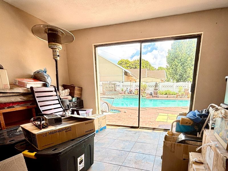 A living area featuring large sliding glass doors that provide direct access to an outdoor patio and swimming pool area.