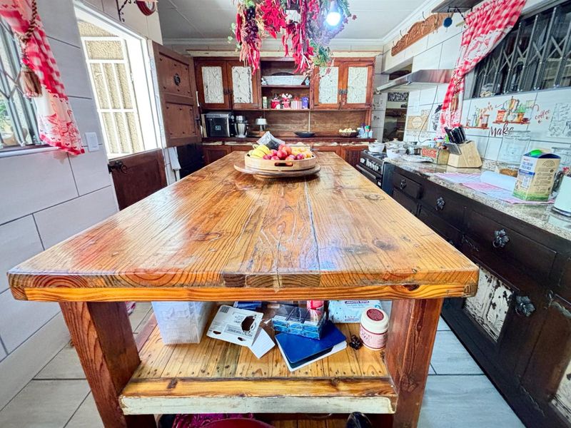 Rustic-style kitchen featuring a large wooden central island, dark cabinetry, granite countertops, and tiled flooring with direct access to the exterior.