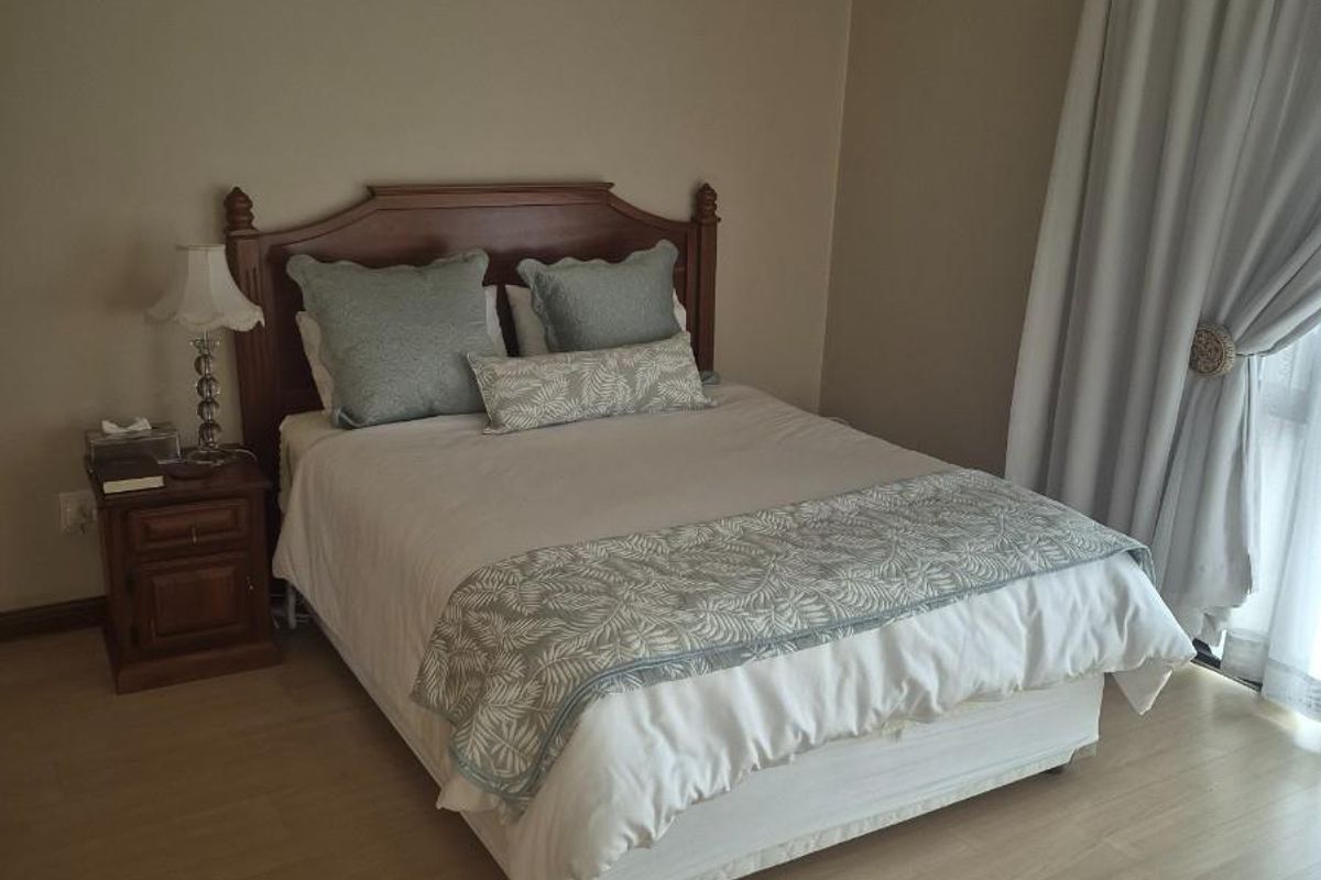 A well-maintained bedroom featuring light-toned laminate flooring and coved ceiling cornices, providing a neutral and comfortable living space.
