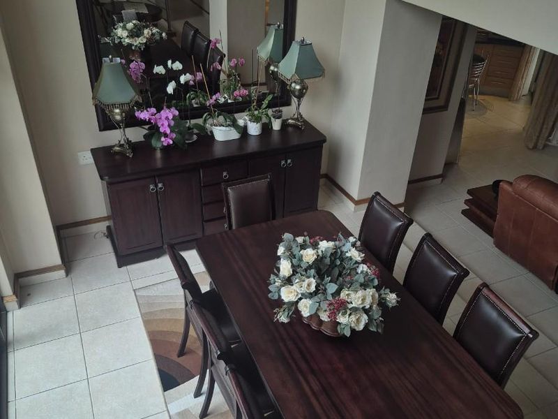 A spacious dining area featuring tiled flooring, viewed from an elevated position, with an open-plan layout leading to adjacent living spaces.