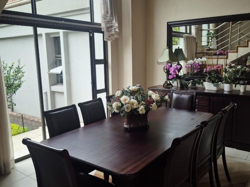 A bright dining room featuring large floor-to-ceiling windows that provide ample natural light and a view of the exterior.