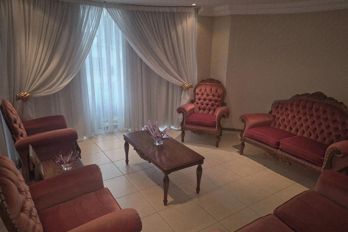 A formal living room featuring tiled flooring, recessed downlights, and large windows dressed with floor-to-ceiling curtains.