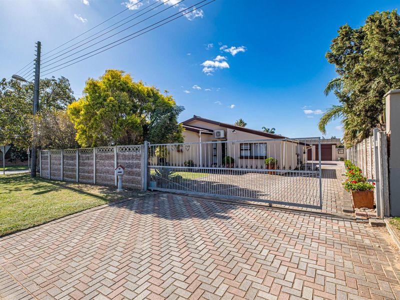 Front view of the property featuring a paved driveway, secure sliding gate, and precast boundary wall, leading to the main house entrance.