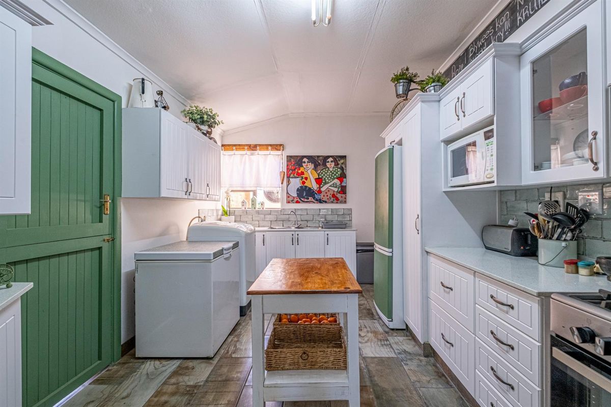 A well-maintained kitchen featuring white cabinetry, tiled splashbacks, integrated appliances, and durable tiled flooring, offering a functional and bright workspace.