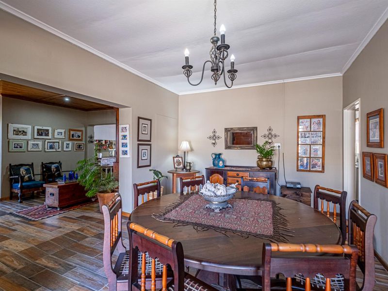 A dining room featuring tiled flooring, a wrought iron chandelier, and an open-plan layout connecting to an adjacent living area.